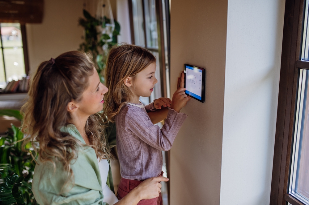 young girl helping her mother adjust the temperature on the thermostat